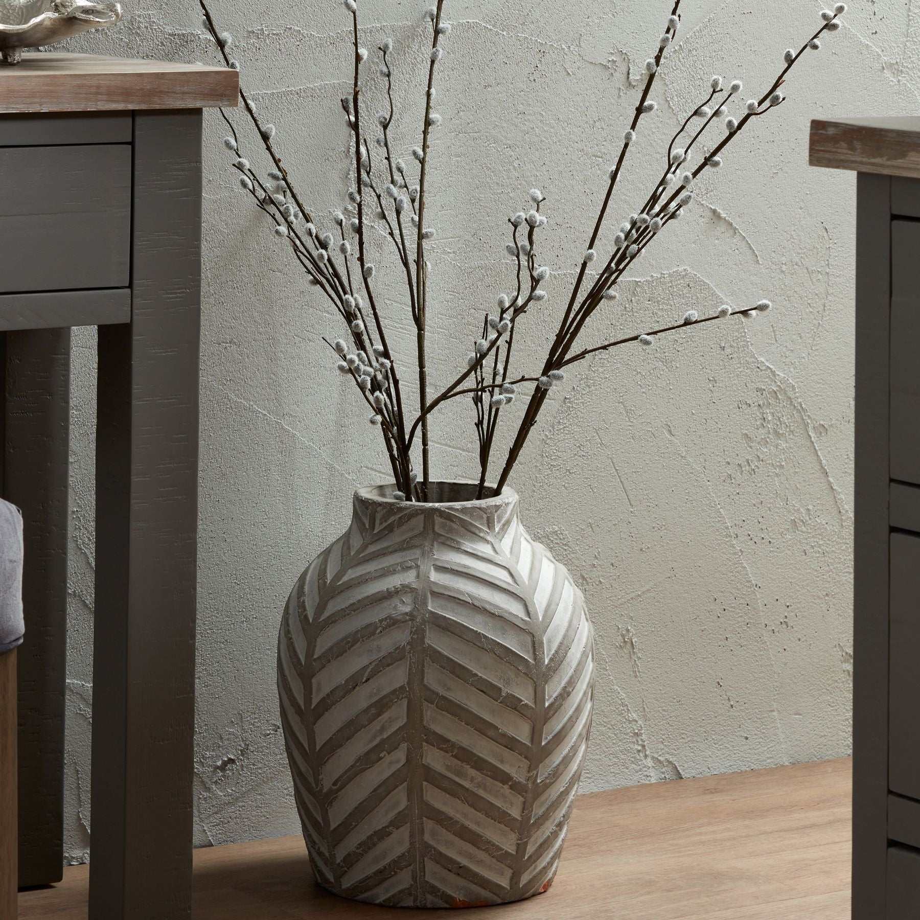 Patterned stone vase with geometric design on a wooden floor.