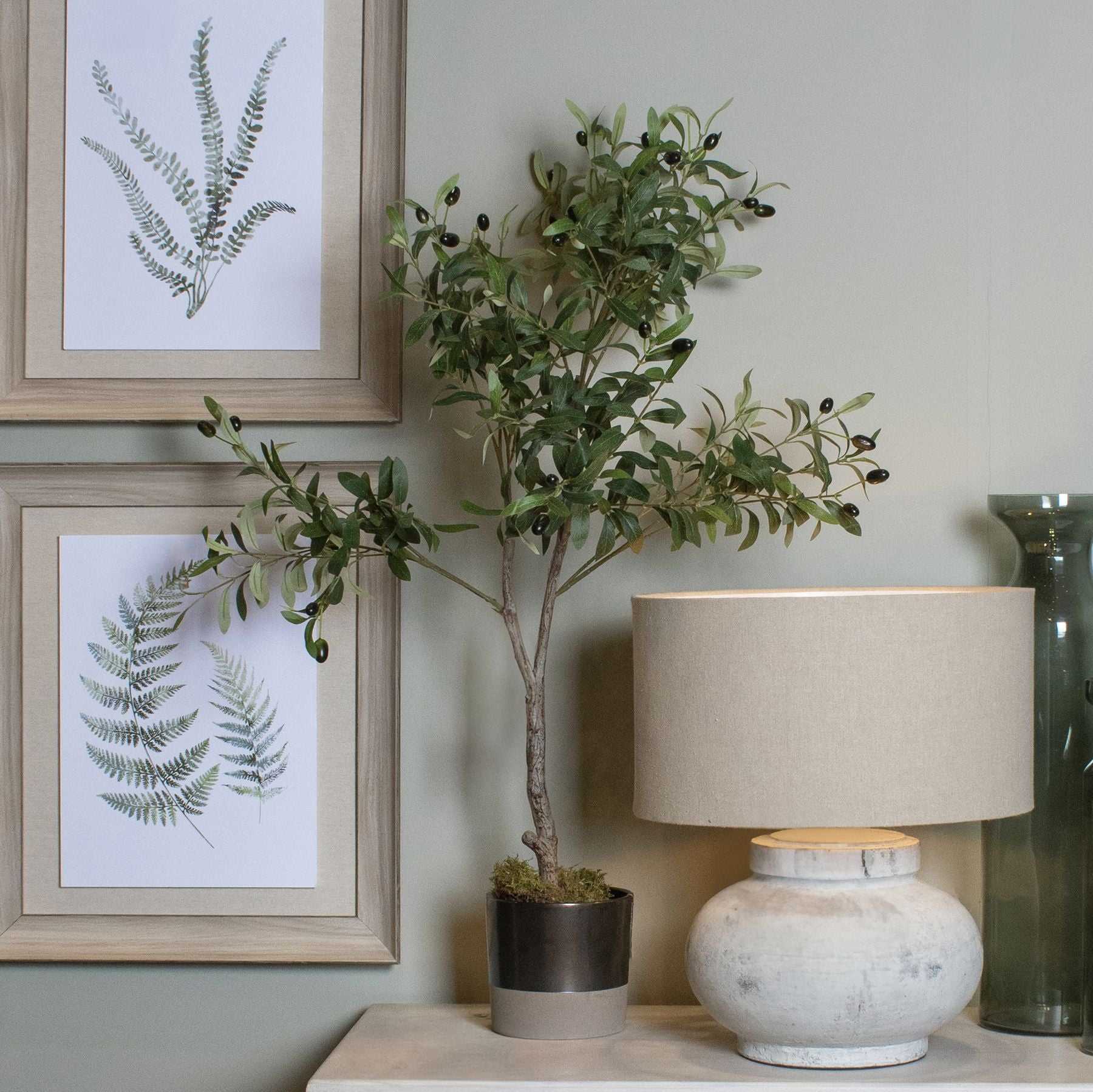 Faux olive tree with lifelike foliage and textured trunk in a stylish indoor setting.