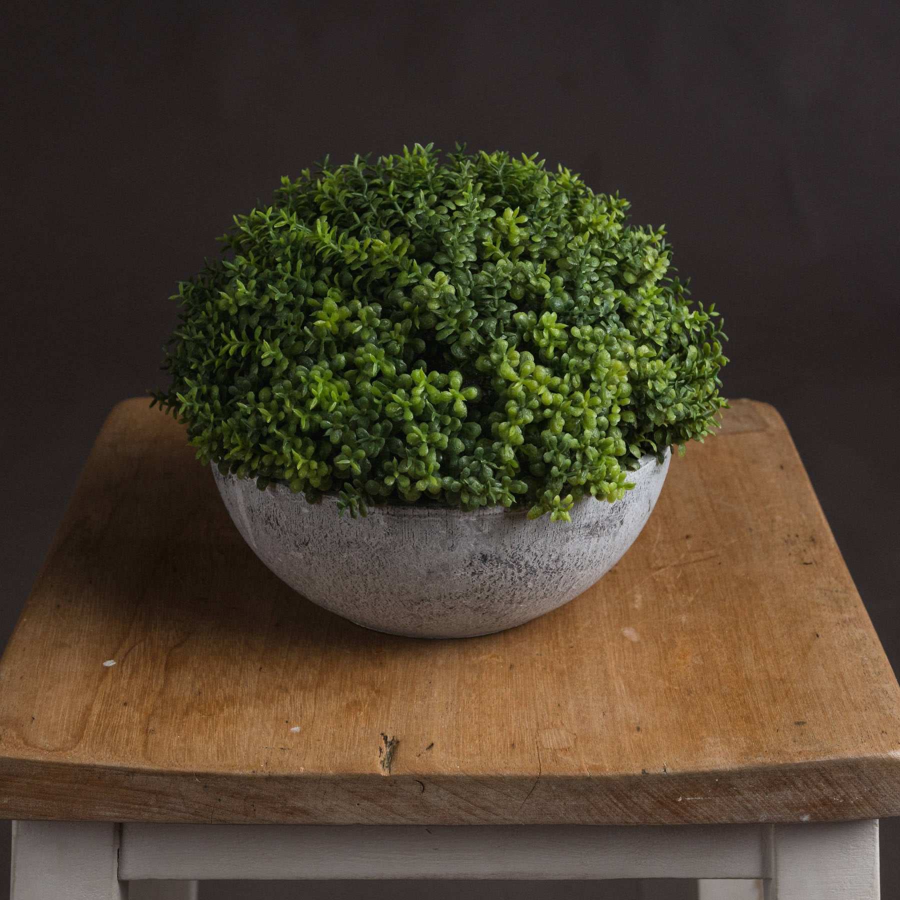 Realistic faux plant with handcrafted leaves in aged grey pot, 15cm dimensions.