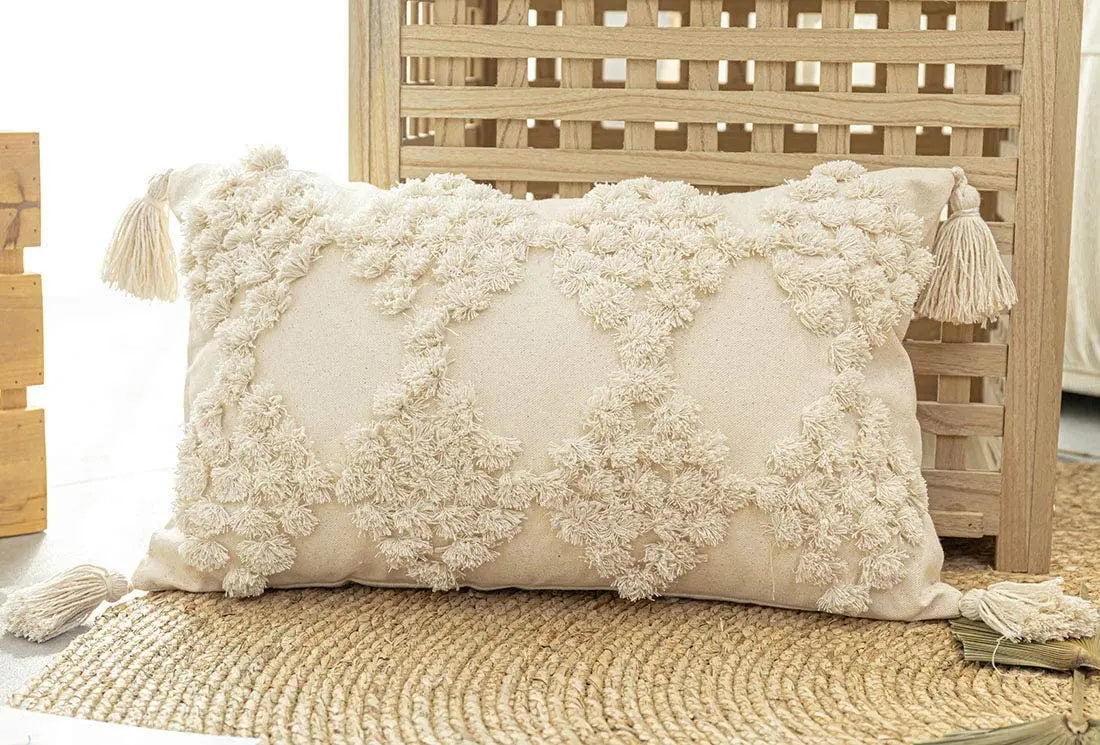 Moroccon style pillow case with intricate patterns and tassels on a woven surface.