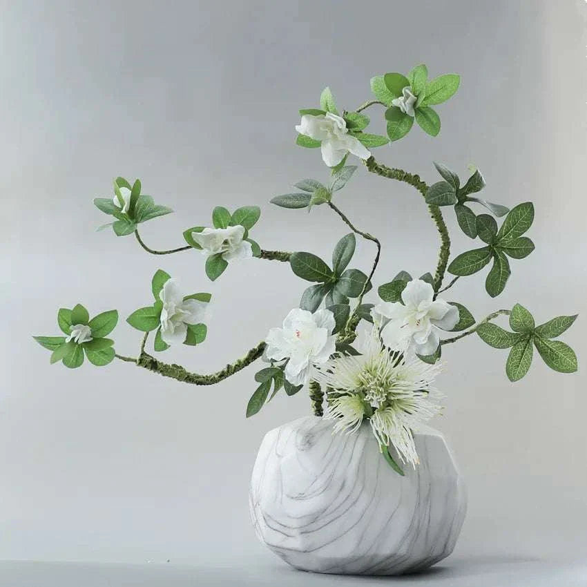 Faux Azaleas Branch in marble vase enhancing interior decor.