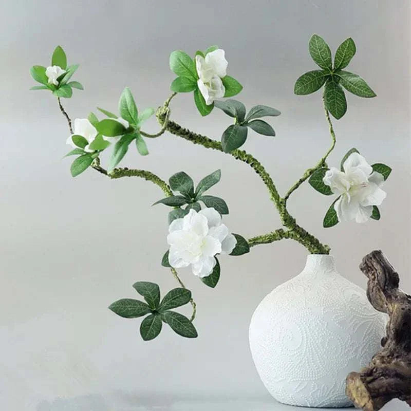 Faux Azaleas Branch in white vase adds elegant greenery to home décor.