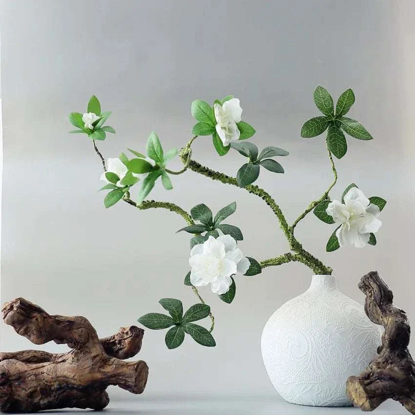 Faux Azaleas Branch in decorative white vase with driftwood accents.