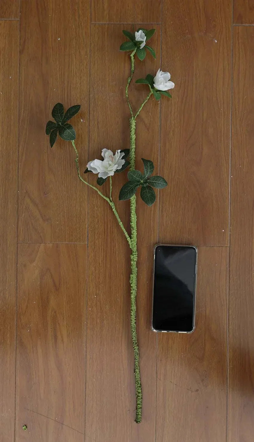 Faux Azaleas Branch on wooden floor with smartphone for scale.