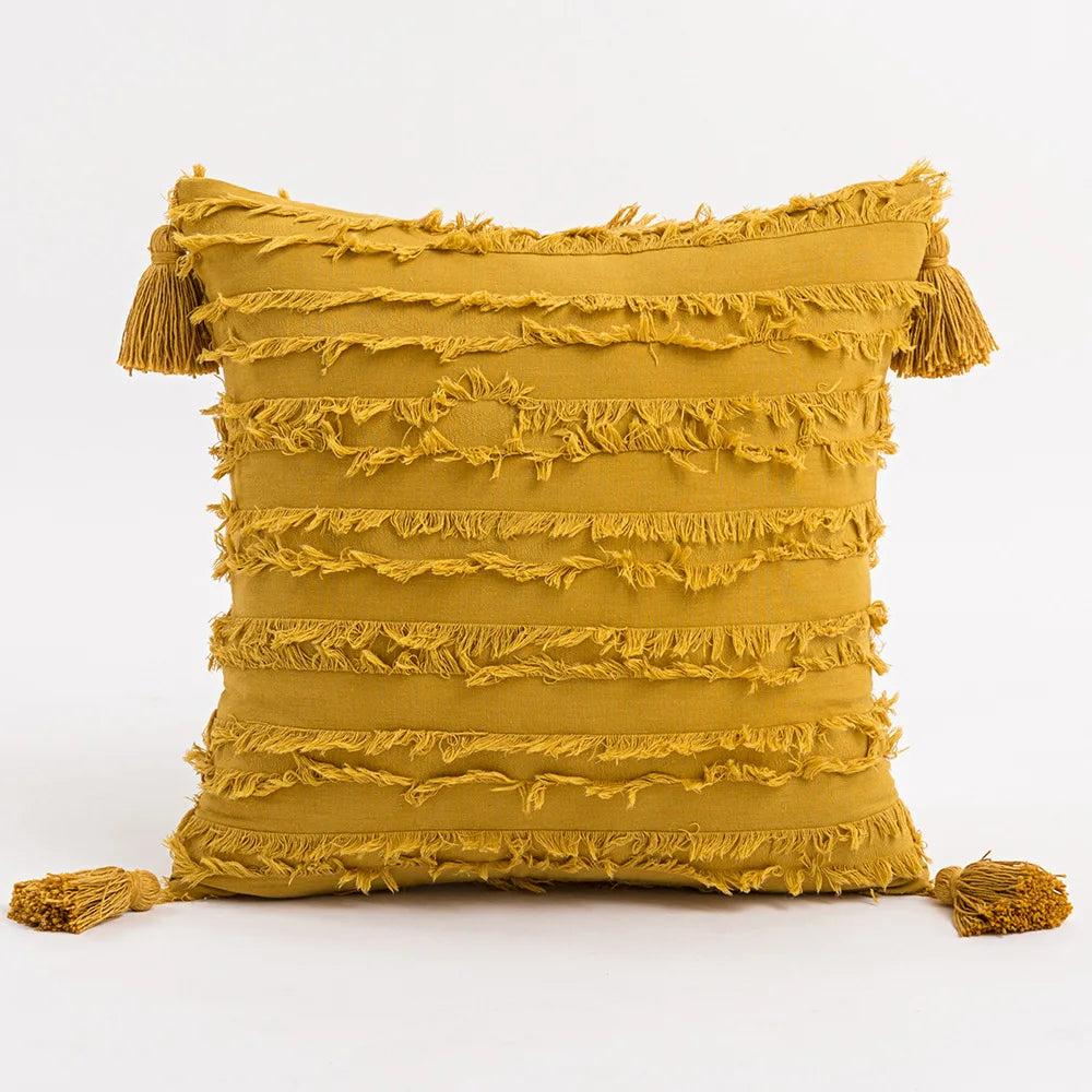 Moroccon style pillow case with intricate yellow patterns and tassels.
