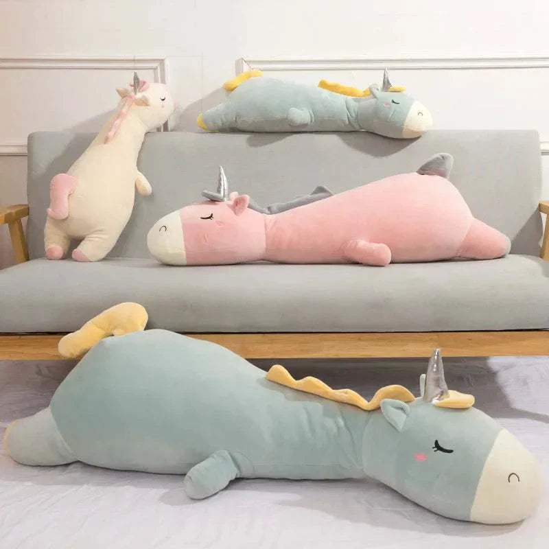 Giant unicorn pillow in various pastel colors on a sofa for magical comfort.