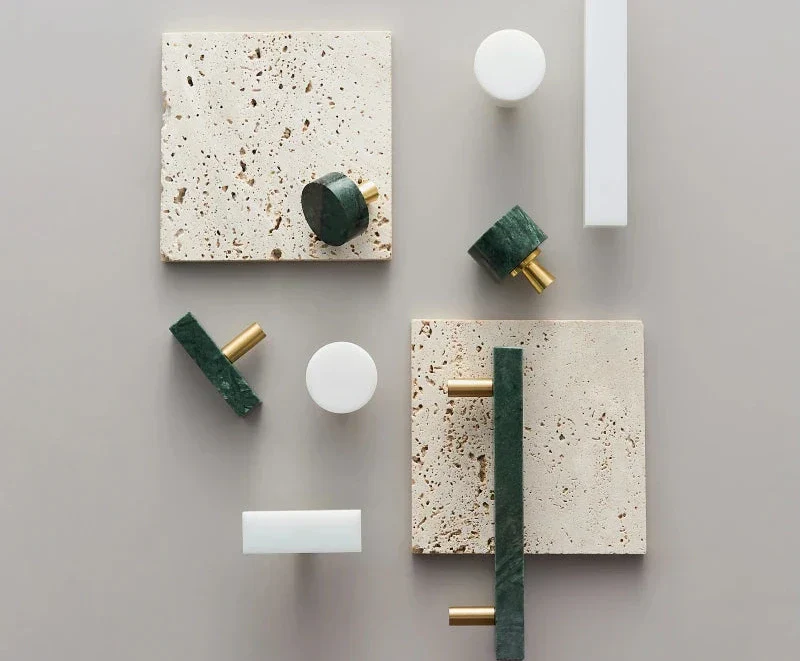 Anessa Handles made of brass with white and green marble accents displayed on beige tiles.