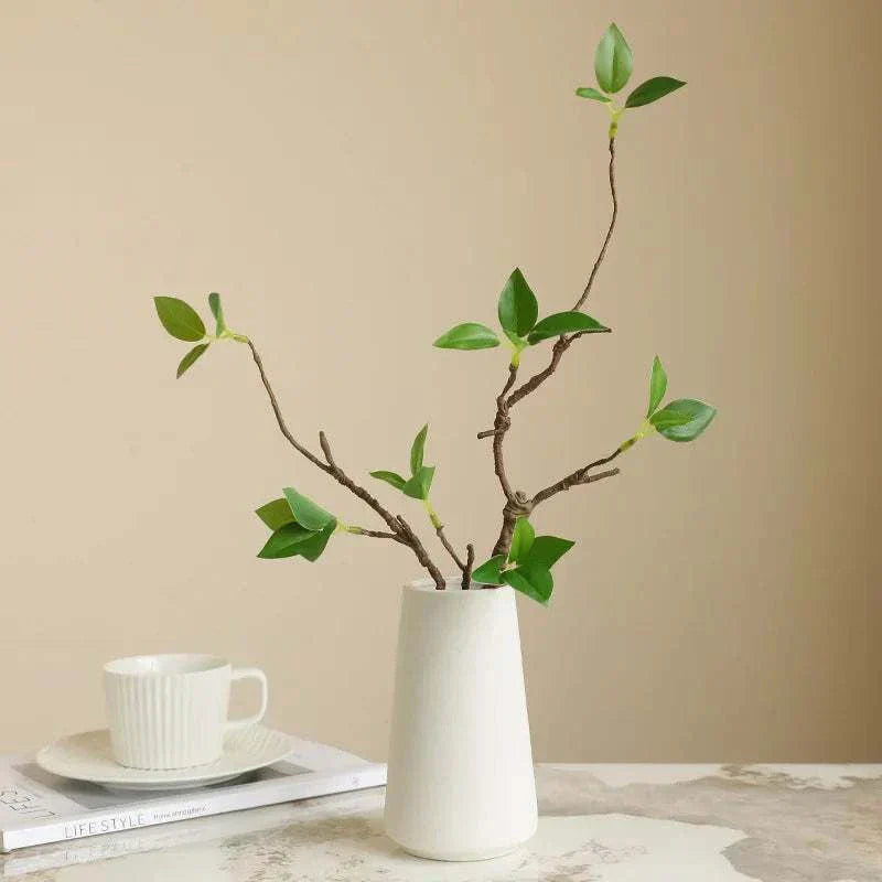 Faux withered branches in a white vase for home decor.