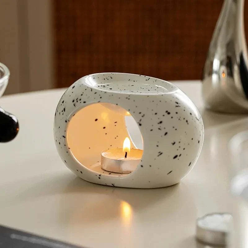 Reis Candle Burner made of durable ceramics with a burning candle inside.