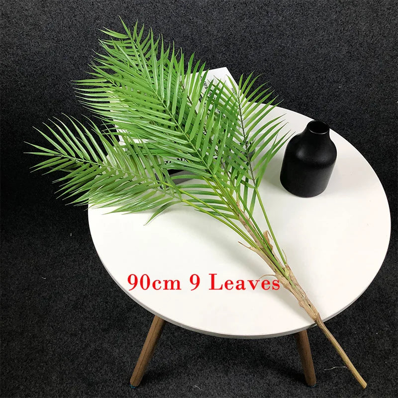 Faux palm tree branch on round white table, lifelike tropical decor.