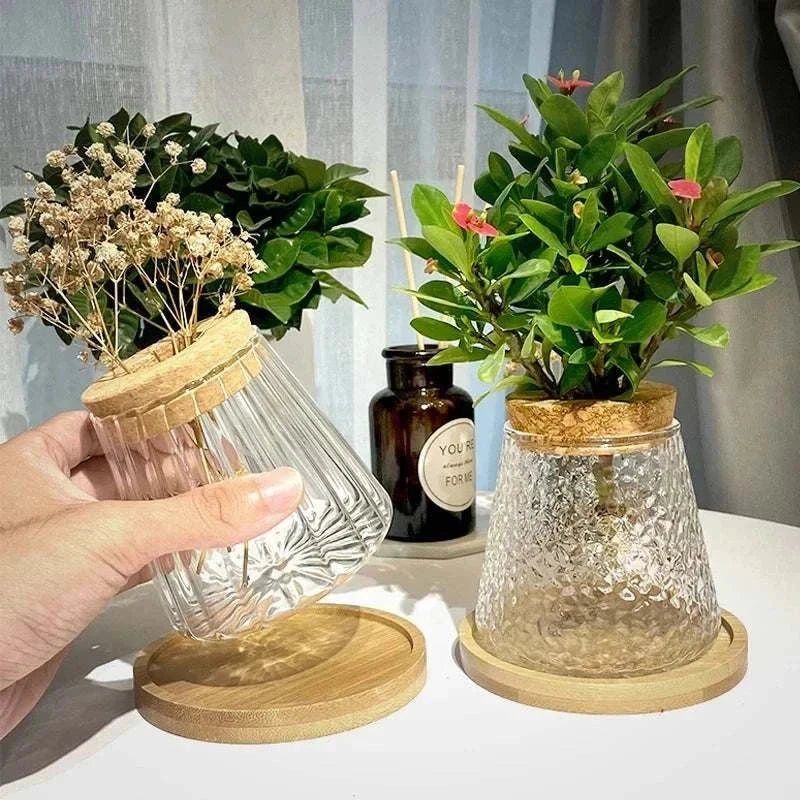 Volcanic style vase with wooden cap, glass bottle, and bamboo base displaying greenery.