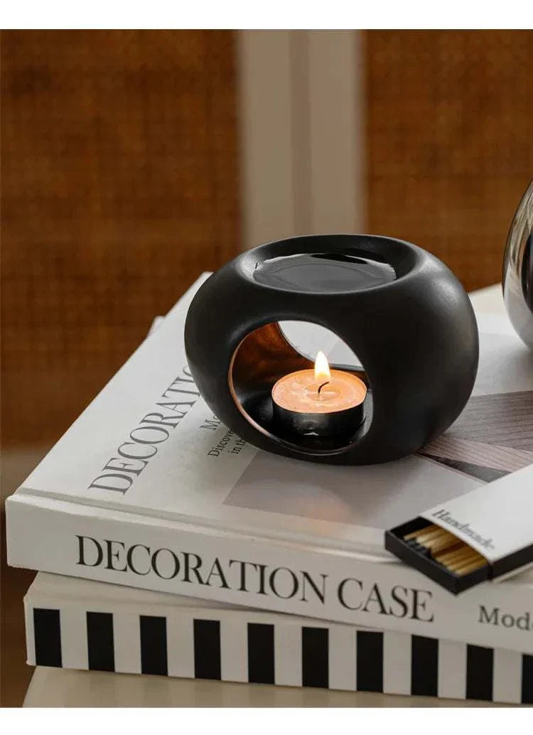 Reis Candle Burner made of durable ceramics on books, gently warming candle for aromatherapy.