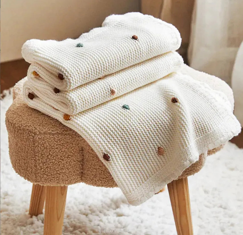 Zion Baby Blanket on a stool, showcasing soft, luxurious material.