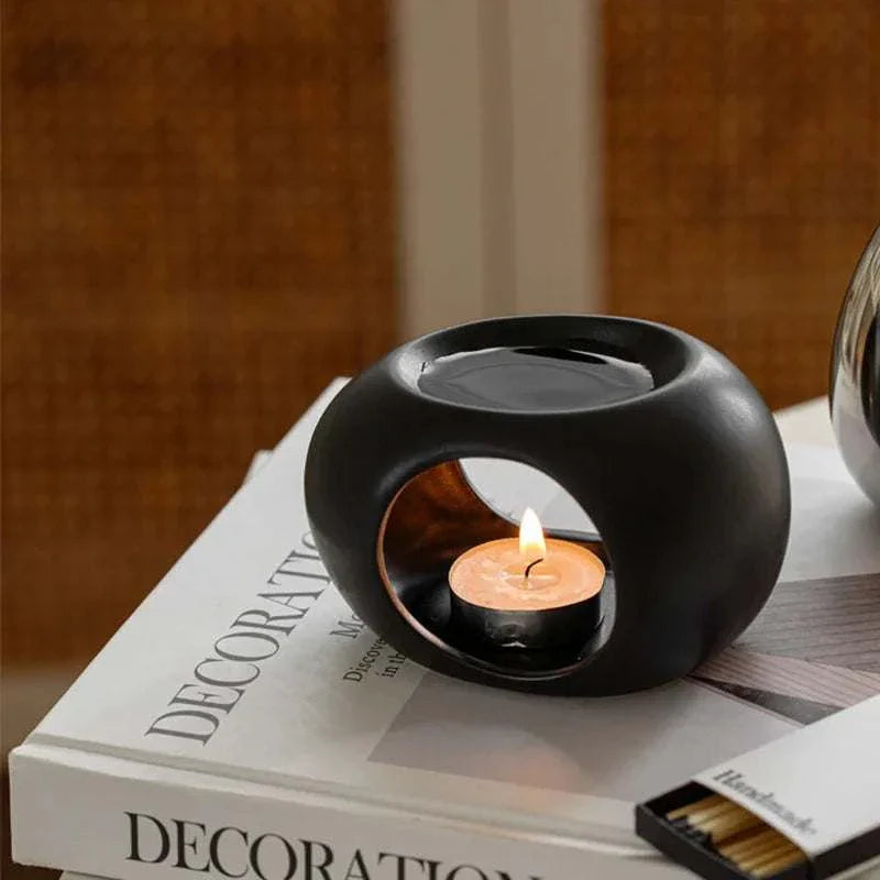 Reis Candle Burner made of ceramic, gently warming scents and oils, placed on a decorative book.