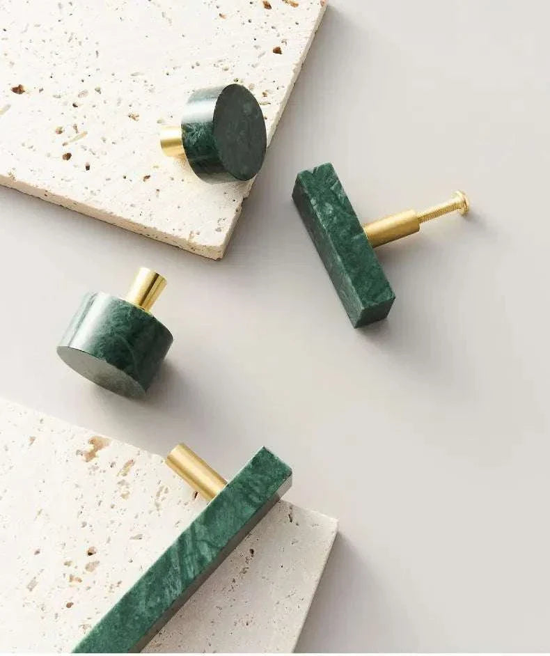 Anessa Handles in brass with white and green marble design displayed on a beige surface.