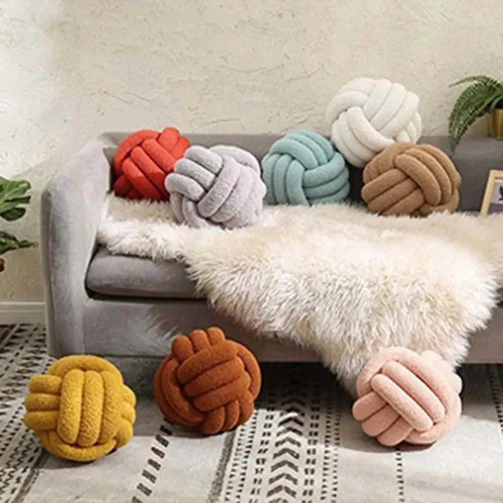 Knotted Ball Pillow in various colors on a couch, perfect for kids' rooms.