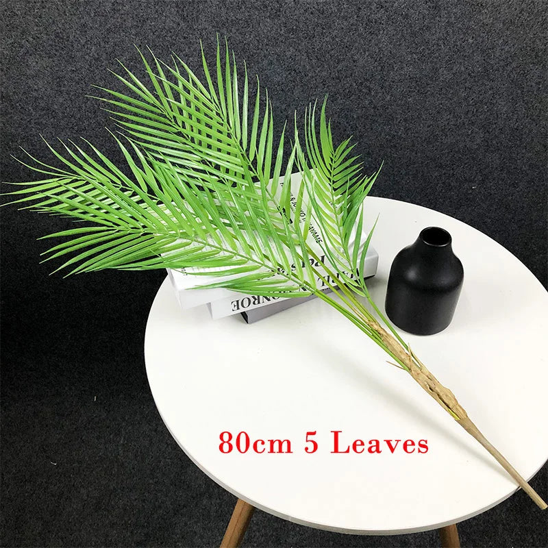 Faux palm tree branch with 5 leaves on a white table for home decor.