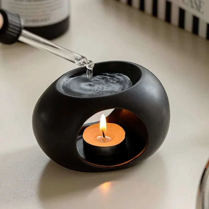 Reis Candle Burner made of durable ceramics with a lit candle and essential oil dripper.
