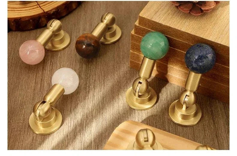 Natural crystal and brass furniture handles in assorted colors on wooden surface.