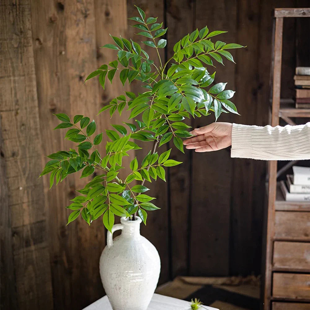 Realistic Alexis Faux Palm Tree Branch in a ceramic vase adding tropical elegance indoors.