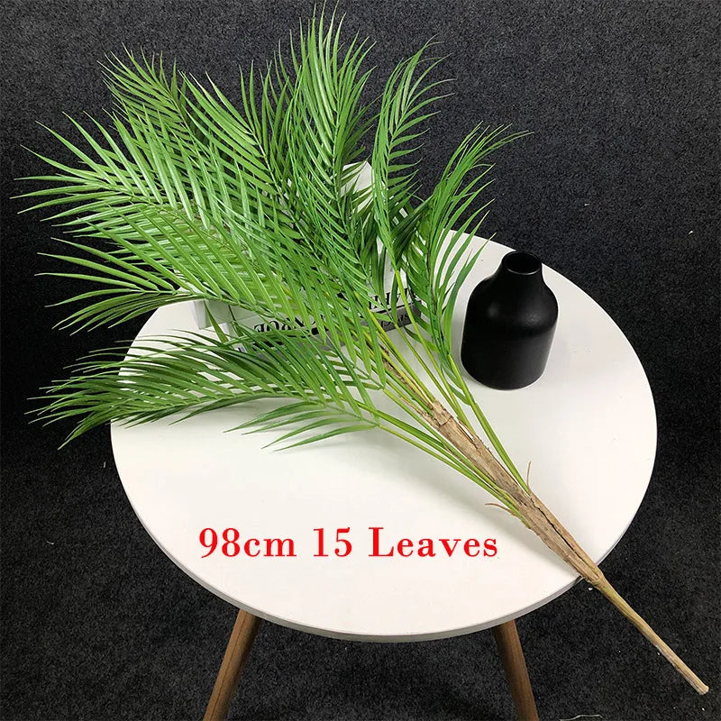 Lifelike faux palm tree branch on a table with a black vase, featuring 15 leaves and measuring 98cm.