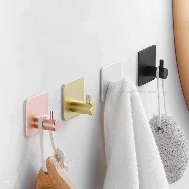 Adhesive wall hooks holding various items on a wall.