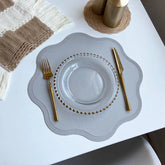 Noah's Placemats in elegant design with glass plate and gold cutlery on a dining table.