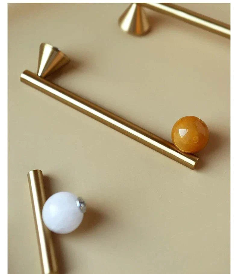 Natural crystal and brass furniture handles with pink decorative knobs for cabinets.