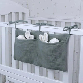 Arian Baby Crib Storage Bag hanging on a crib, made of soft cotton with pockets for nursery essentials.
